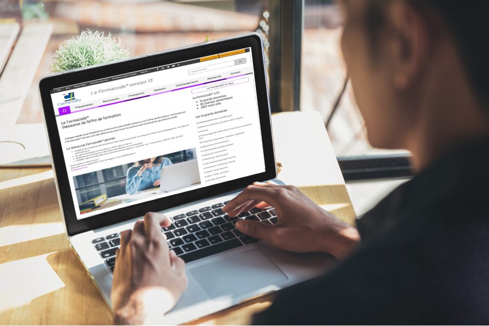 Un homme utilise un ordinateur portable pour parcourir des informations sur la rénovation sur le site Internet du Centre INFFO, avec une page violette affichée sur son écran.