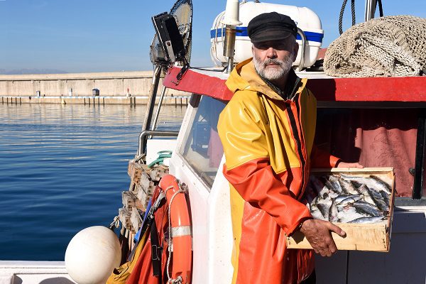 Un marins-pêcheurs de Rennes tenant une caisse de poissons sur un bateau.