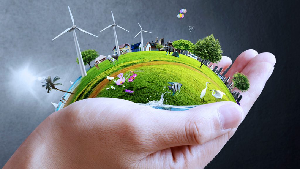 La main d'une personne tenant une planète verte avec des éoliennes, mettant en valeur la transition écologique vers la formation d'une industrie durable.