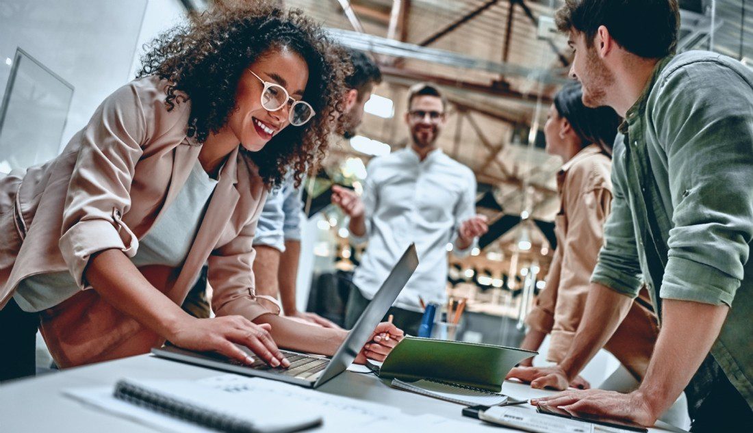 Un groupe de personnes collaborant sur un ordinateur portable pour améliorer leur expérience d'apprentissage et approfondir leur compréhension de l'économie et du marché du travail.