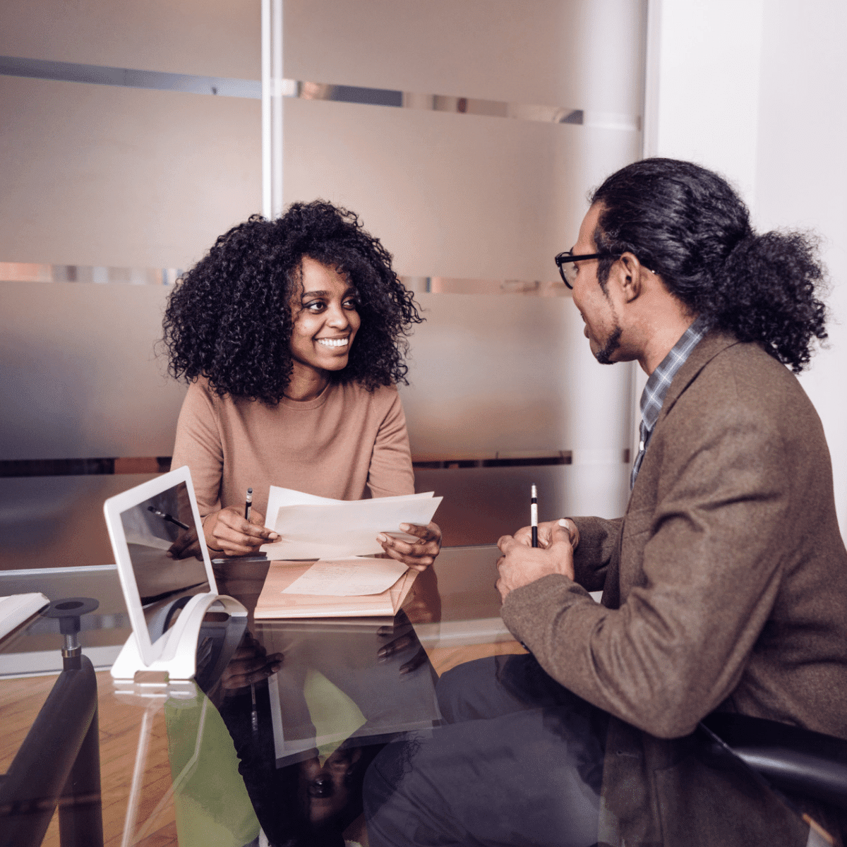 Un homme et une femme discutant d'une demande d'emploi à un bureau dans un bureau, se concentrant sur l'élaboration d'une lettre de motivation percutante.